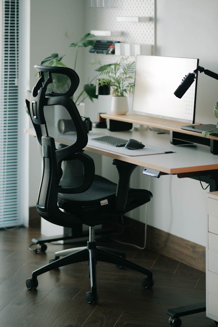 A sleek home office setup featuring a mesh ergonomic chair, desk, and greenery for a refreshing work environment.